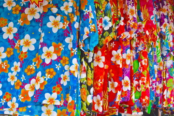 Typical summer seaside holiday outfit with flower print on. Plenty of colourful Hawaiian style shirts hanging on a local market. No fitting rooms available. Perpignan, France, Europe