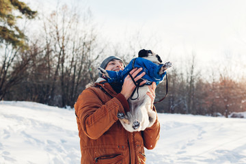 Fototapeta na wymiar Pug dog walking with his master. Man playing with his pet and having fun. Puppy wearing winter coat.