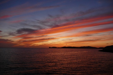 Fototapeta na wymiar Sunset in Alghero, Sardinia, Italy. Capo Cassia in the background.