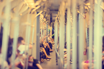Blurred images of stainless steel poles and many passengers sitting and playing smartphone daily life of the city society in sky train. BTS in Bangkok, Thailand. Blurry people background.