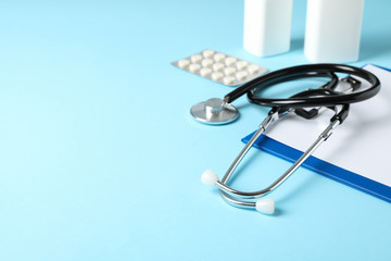 Stethoscope, tablet and medicine on blue background, space for text