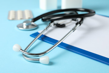 Stethoscope, tablet and medicine on blue background, close up