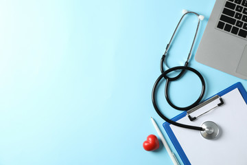 Stethoscope, laptop, tablet, pen and heart on blue background, space for text