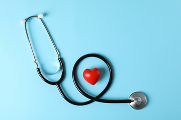 Stethoscope and heart on blue background, top view