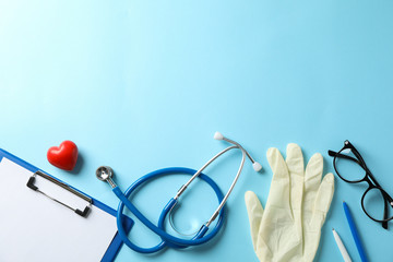 Stethoscope and glasses on blue background, space for text. Doctor workplace