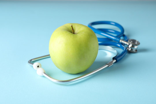 Stethoscope and apple on blue background, close up. Healthcare