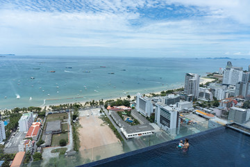 Baby with father swim in swimming pool in Pattaya city at high floor of one condominium in summer. Good view at the sea, luxury resort