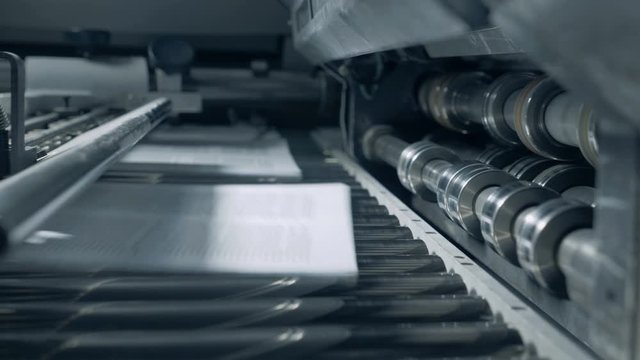 Printing conveyor with paper sheets moving along it