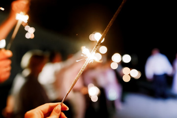 A crowd of young happy people with sparklers in their hands during celebration. Sparkler in hands...