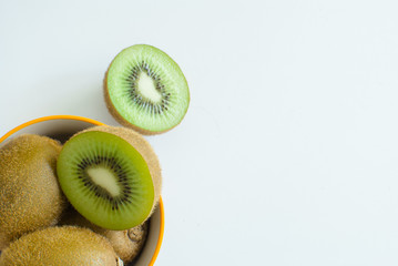 Top view of many sliced of kiwifruits in bowl on a white background with copy space.