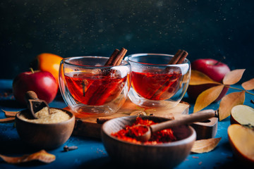 Hot tea with cinnamon sticks on blue background