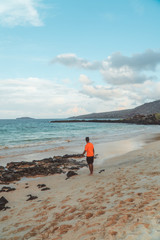 Man tourist on Galapagos beach. Tourist man walking along Tropical beach with turquoise ocean waves and white sand. Sand bay view. Holiday, vacation, paradise, summer vibes. Isabela, San Cristobal