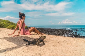 Foto op Canvas Galapagos beach iguana and woman tourist on beach. Natural wildlife shot in San Cristobal, Galapagos. Beautiful beach with ocean sea background. Wild animal in nature. © Jam Travels