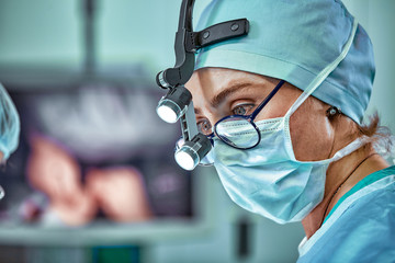 Female surgeon in operation room with reflection in glasses - Powered by Adobe