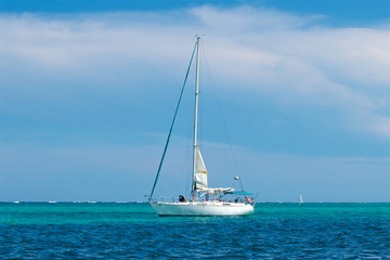 Fototapeta premium Sailboat at anchor in turquoise and blue water at San Pedro Belize