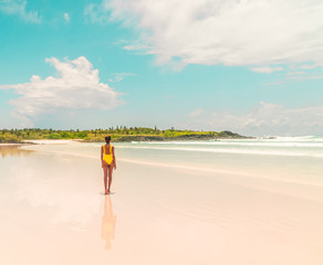Yellow bikini Woman on beach. Tourist walking along Tropical Galapagos beach with turquoise ocean...