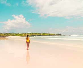 Yellow bikini Woman on beach. Tourist walking along Tropical Galapagos beach with turquoise ocean waves and white sand. Holiday, vacation, paradise, summer vibes. Isabela, San Cristobal