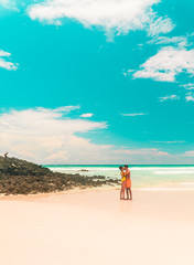 Fototapeta na wymiar Couple kissing beach holiday romance. Tourist on Tropical beach with turquoise ocean waves and white sand. Sand bay view. Holiday, vacation, paradise, summer vibes. Isabela, San Cristobal
