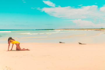Woman, Iguana playing on beach Galapagos. Tourist on Tropical beach with turquoise ocean waves and white sand. Sand bay view. Holiday, vacation, paradise, summer vibes. Isabela, San Cristobal