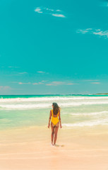 Fototapeta na wymiar Woman walking on Galapagos beach. Tourist walking along Tropical beach with turquoise ocean waves and white sand. Sand bay view. Holiday, vacation, paradise, summer vibes. Isabela, San Cristobal