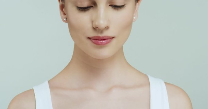 Close up of the female Caucasian bottom part of face, shoulders and neck on the white background, then camera moving up to the face of smiling woman. Health and beauty care.