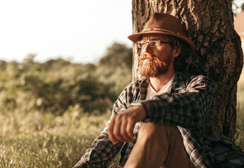 Thoughtful traveler resting near tree