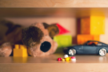 a bunch of multi-colored pills on the background of blurry children's toys