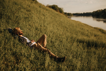 Male traveler resting on hill near river