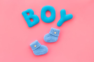 Children's birthday concept. Word boy near booties on pink background top view