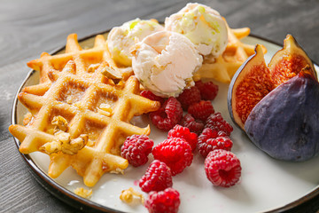 Plate with tasty waffles, berries and fig on table, closeup