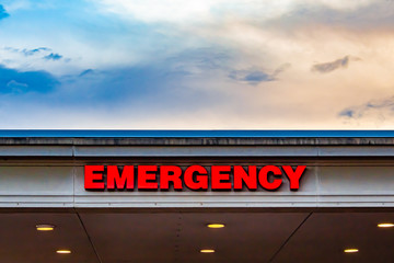 A hospital's emergency ward sign by the evening sky