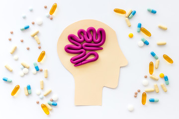 Treat brain diseases. Head with plastiline meanders and pills on white background top view