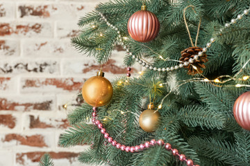 Obraz na płótnie Canvas Decorated Christmas tree near brick wall, closeup