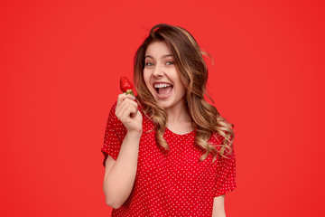 Excited woman in bright dress carrying strawberry