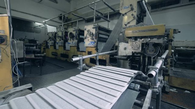 Printed sheets of paper are moving along the industrial transporter