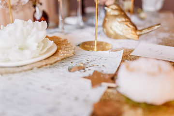 New Year mood. Table with a gold tablecloth, decorated with candles for celebration. Festive still life by candlelight. Graphics of beautiful calligraphy with a flower on a plate.