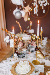 New Year mood. Table with a gold tablecloth, decorated with candles for celebration. Festive still life by candlelight. Graphics of beautiful calligraphy with a flower on a plate.