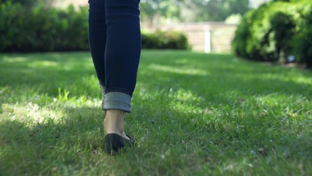 Low angle shot of Young woman walking outside in city park during the day. Focused only on the feet and shoes with shallow depth of field 