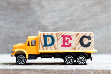 Truck hold letter block in word dec on wood background (Concept for month December)
