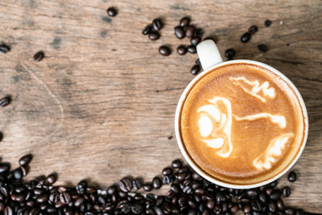 Latte art coffee in cup on wooden table with coffee bean