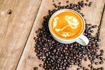 Latte art coffee in cup on wooden table with coffee bean