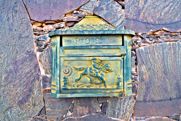 Old classic green mail box on a stone wall.