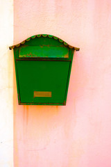 Weathered green letter box or mailbox on a pink wall.