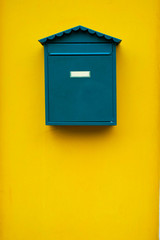 Elegant simple green mail box on a yellow wall.