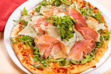 Italian Cuisine. Pizza with prosciutto, ham, arugula and parmesan