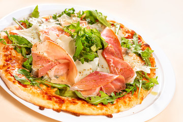 Fototapeta na wymiar Italian Cuisine. Pizza with prosciutto, ham, arugula and parmesan