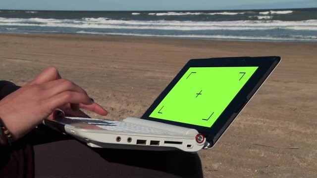 Man using Laptop with Green Screen on a beautiful Beach. You can Replace Green Screen with the Footage or Picture you Want with “Keying” effect in After Effects (check out tutorials on YouTube). 