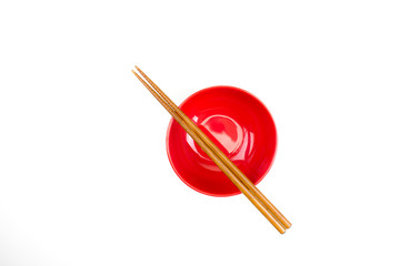 Close-up of a red bowl with wooden chopsticks on isolated background.