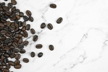 Close up, brown coffee beans on a marble pattern background with copy space. Top view.