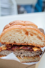 Delicious last-minute gourmet hamburger cut in half with cheddar bacon with small tomatoes Classic american fast food background. Cut in half burgers with grilled meat and onions on wood. Hamburgers w